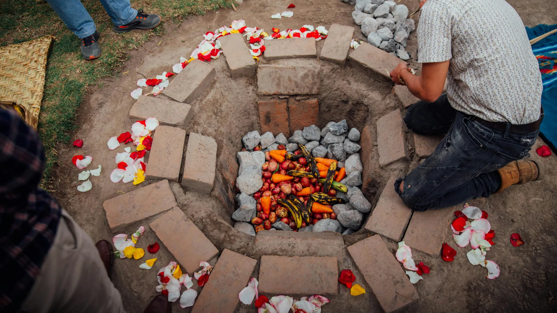 Traditional underground oven in Otavalo, Ecuador with vegetables and petals.